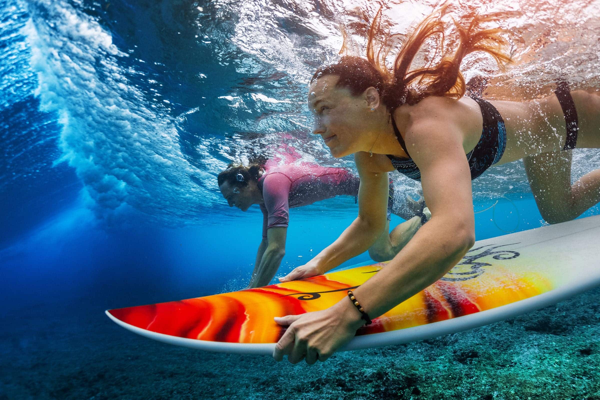 Couple surfing diving under wave