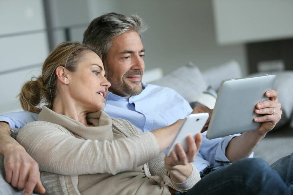 Middle aged man and woman looking at devices